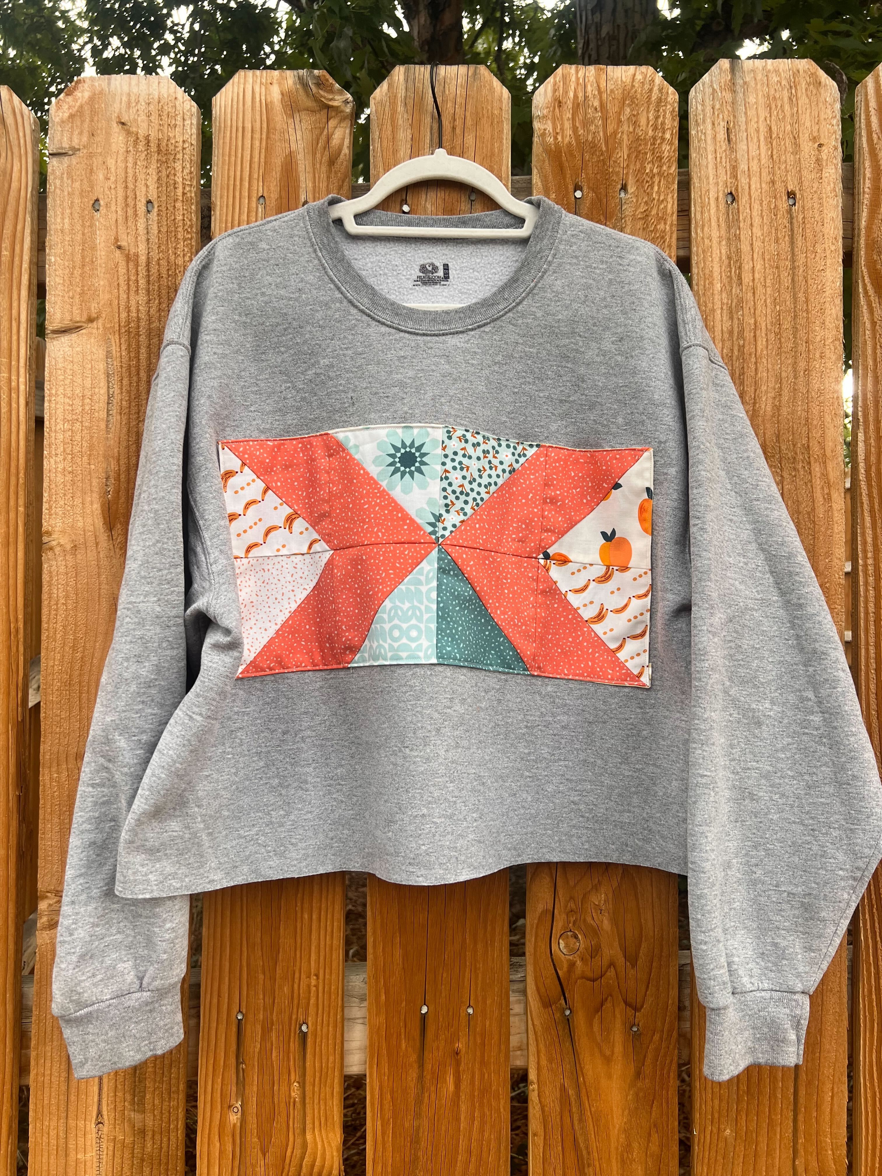 Long sleeve sweater with quilted block sewn on front.