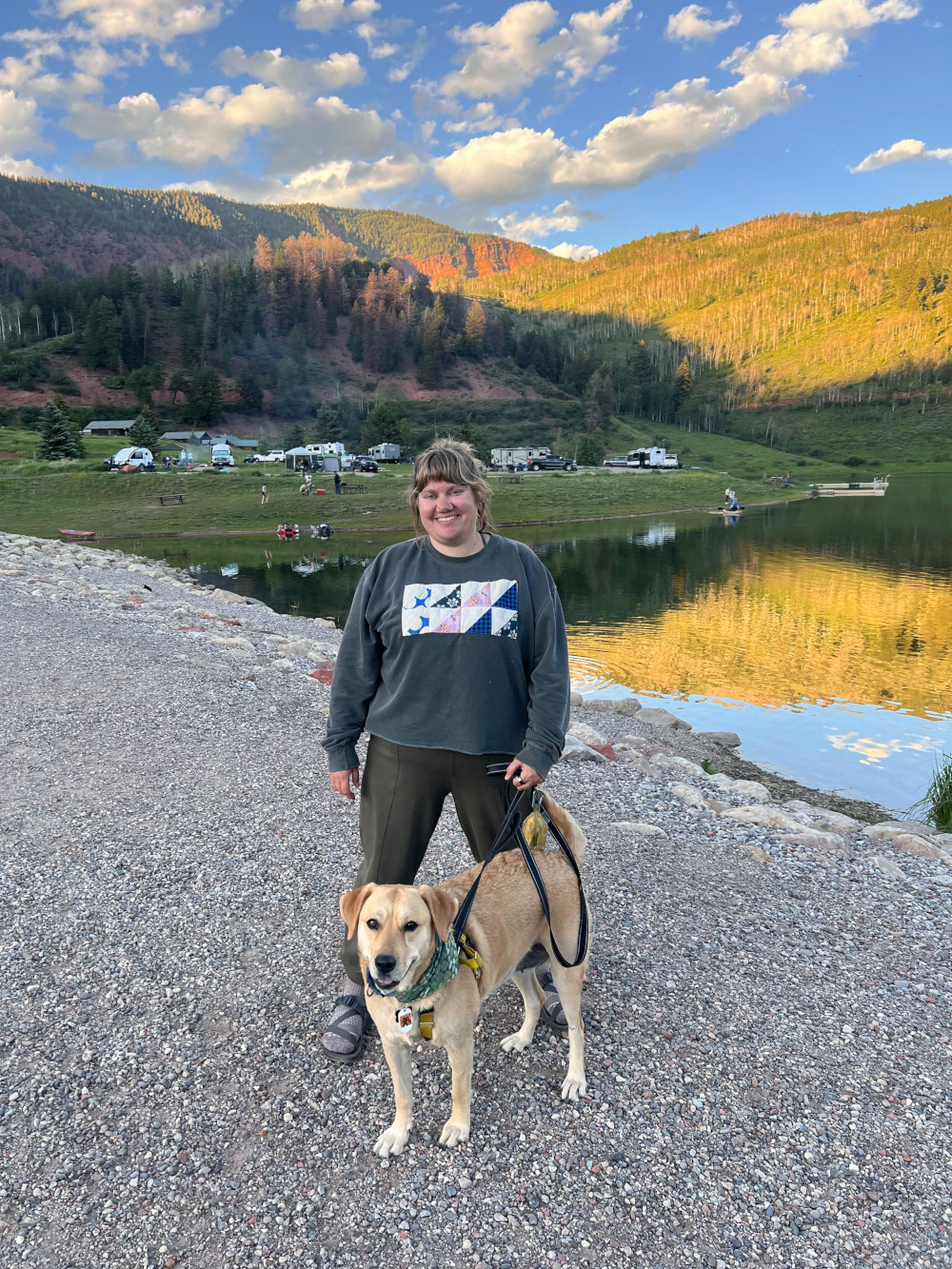 Courtney with her dog Yarrow, in front of a lake.